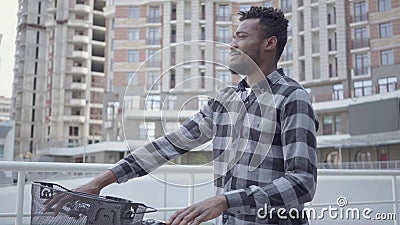 Portret knappe Afrikaanse Amerikaanse mens die zich met fiets tegen de achtergrond van stedelijke architectuur bevinden De kerel stock footage Portret knappe Afrikaanse Amerikaanse mens die zich met fiets tegen de achtergrond van stedelijke architectuur bevinden De kerel stock footage
