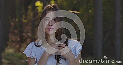 Portret van een bedachtzaam Kaukasisch bruin meisje met bruine ogen die tussen bomen staan in het zomerbos Charming stock footage Portret van een bedachtzaam Kaukasisch bruin meisje met bruine ogen die tussen bomen staan in het zomerbos Charming stock footage