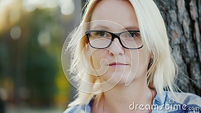 Portret van een boeiende jonge vrouw in een bril Hij kijkt naar de afstand, de wind speelt met haar haar haar Sits in een stock video Portret van een boeiende jonge vrouw in een bril Hij kijkt naar de afstand, de wind speelt met haar haar haar Sits in een stock video