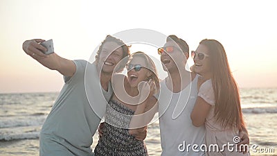 Portret van Vier Vrienden die Selfie nemen samen Gebruikend Smartphone op de Kust tijdens Windy Weather stock footage Portret van Vier Vrienden die Selfie nemen samen Gebruikend Smartphone op de Kust tijdens Windy Weather stock footage