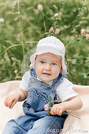 Portriat of adorable, charming toddler girl in flowers meadow. Smiling happy baby child on summer day with colorful flowers, Stock Photo