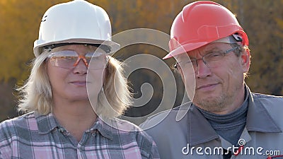 Porträt von Bauarbeitern ein Mann und eine Frau in einem Sturzhelm, der Kamera betrachtet stock footage Porträt von Bauarbeitern ein Mann und eine Frau in einem Sturzhelm, der Kamera betrachtet stock footage