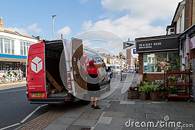 09/29/2020 Portsmouth, Hampshire, UK A DPD parcel delivery driver carrying parcels from his van doors into a shop Editorial Stock Photo