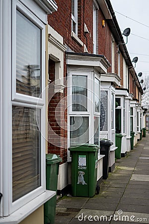 The exterior of typical english brick terraced houses with green wheelie bins at the front Editorial Stock Photo