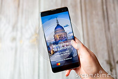 03-22-2021 Portsmouth, Hampshire, UK A mobile phone or cell phone being held in a hand with the Welcome to london app open on Editorial Stock Photo