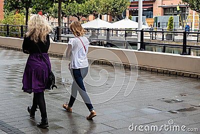 Two women walking together in the rain without umbrellas Editorial Stock Photo