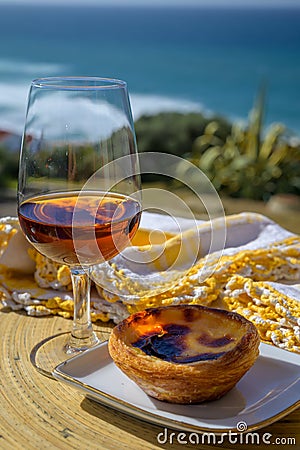Portugal`s traditional food and drink, glass of porto wine or muscatel de setubal and sweet dessert Pastel de nata egg custard Stock Photo