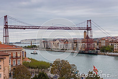 Biscay bridge flying with gondola and boat on river Nervion, toned. Portugalete landmark. Famous bridge called Puente de Vizcaya. Editorial Stock Photo