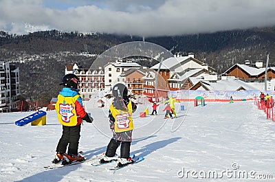 Posa Khutor, Sochi, Russia, January, 26, 2018. Two little boys skiing on the child`s training slope in the background of Olympic Editorial Stock Photo