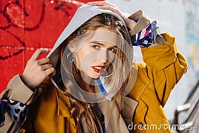 Dark-eyed young photo model wearing silver accessories posing near wall Stock Photo