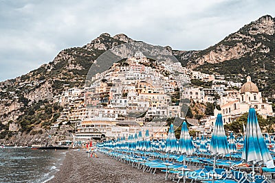 Positano beach with umbrella beds with Amalfi crags in background Stock Photo