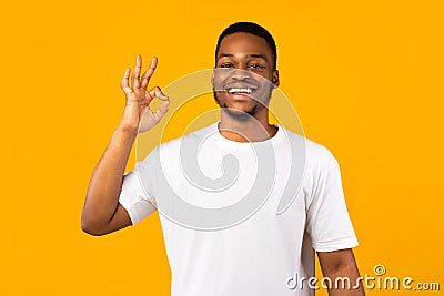 Positive African Man Gesturing OK Sign On Yellow Studio Background Stock Photo