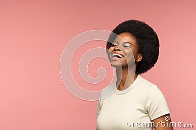 Cheerful african woman happy laughing over pink wall. Delightful young girl smiling with closed eyes Stock Photo