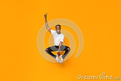 Positive Afro Man Jumping In Air Having Fun In Studio Stock Photo