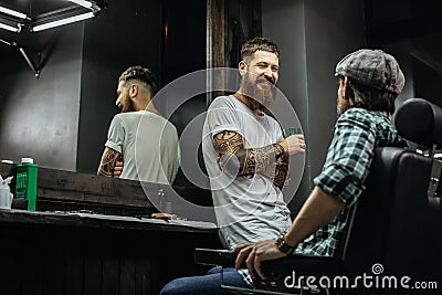 Positive bearded barber looking at his client and smiling Stock Photo