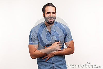 Positive bearded man holding his belly and laughing out loud, chuckling and hysterically laughing with anecdote, having fun Stock Photo