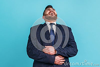 Positive bearded man wearing official style suit holding his belly and laughing out loud, chuckling Stock Photo