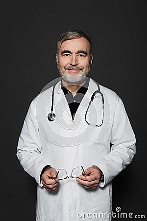 positive bearded physician holding eyeglasses and Stock Photo