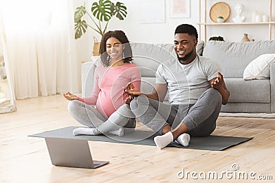 Positive black expecting couple having online yoga class Stock Photo