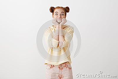 Positive bright girl is all ears to hear fresh rumor. Attractive sincere redhead woman with two buns hairstyle grinning Stock Photo