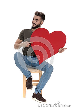Positive casual man pointing and holding a heart Stock Photo