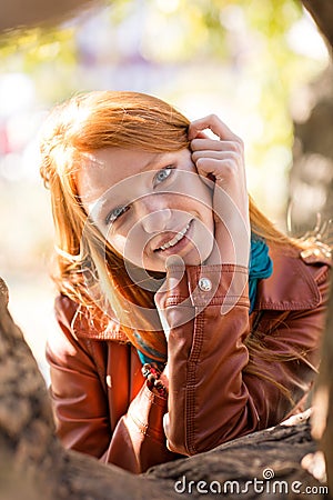 Positive cheerful cute young woman posing near tree in park Stock Photo