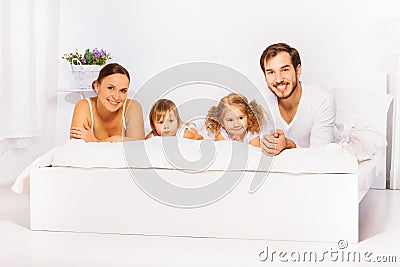 Positive cheerful family laying on white bed Stock Photo