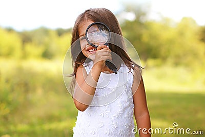 Positive cheerful little girl looking through a magnifying glass Stock Photo