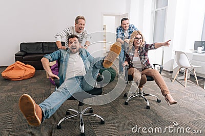 Positive cheerful men pushing office chairs Stock Photo