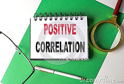 POSITIVE CORRELATION text on notebook on green paper Stock Photo