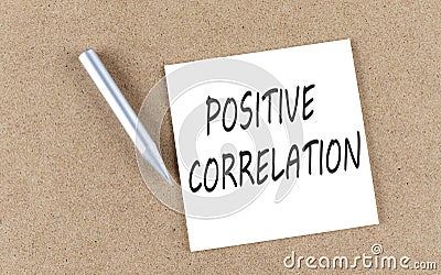 POSITIVE CORRELATION text on a sticky note on cork board with pencil Stock Photo