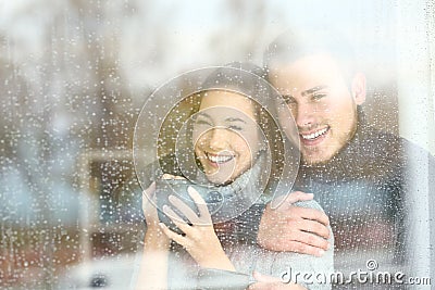 Positive couple looking through a window a rainy day Stock Photo