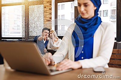 Positive couple pointing at muslim woman Stock Photo