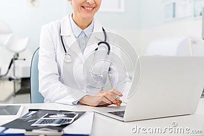 Positive doctor working on laptop in Stock Photo