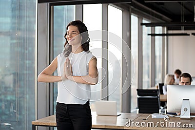 Positive employee doing yoga standing in coworking office during Stock Photo