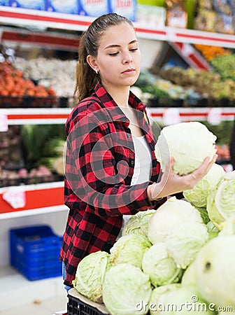 Positive customer chooses cabbages at grocery store Stock Photo