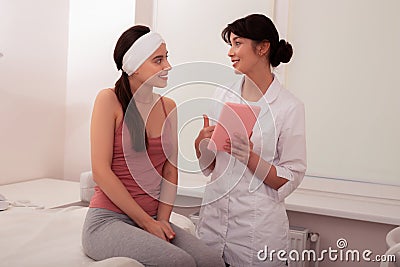 Positive experienced cosmetologist pointing at the tablet screen Stock Photo