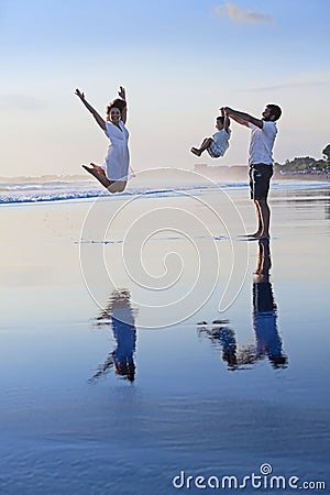 Positive family having fun on black sand sea beach Stock Photo