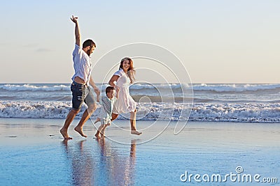 Positive family running along sea edge on the beach Stock Photo