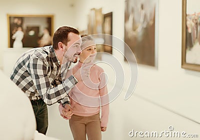 Positive father and daughter regarding paintings in museum Stock Photo