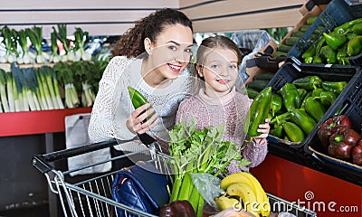 Positive female and cheerful little girl shopping green veggies Stock Photo