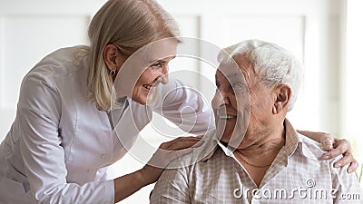 Positive female nurse taking care of senior male patient Stock Photo