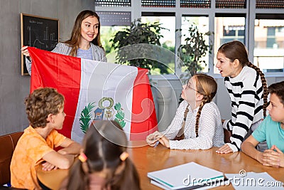 Positive female teacher discussing with preteens students state flag of Peru in auditory of middle school Stock Photo