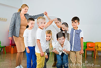 Positive female teacher playing circle game with children in classrom Stock Photo