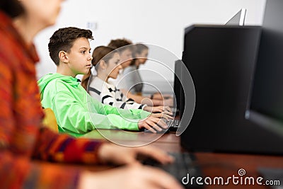 Positive female teacher tells a teenager how to work on computer Stock Photo