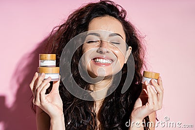 Positive freckled woman holding cosmetic creams Stock Photo