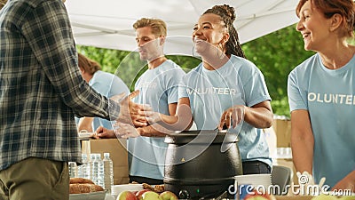 Positive Group of Young Adult Volunteers Serving Free Food for Poor People in Need. Charity Workers Stock Photo