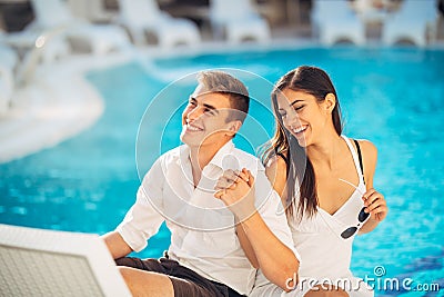 Positive happy couple relaxing by the swimming pool in luxury summer vacation resort.Enjoying time together in spa wellness center Stock Photo