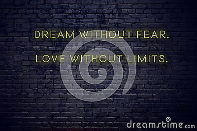 Positive inspiring quote on neon sign against brick wall dream without fear love without limits Stock Photo