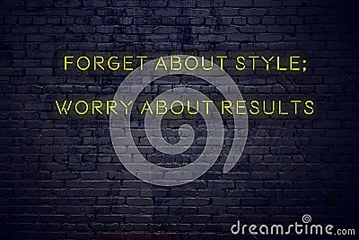 Positive inspiring quote on neon sign against brick wall forget about style worry about results Stock Photo